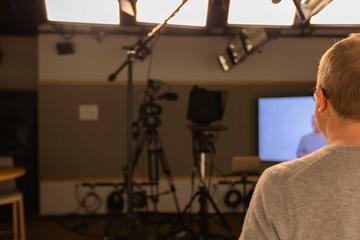 Person standing in a studio environment looking toward a camera