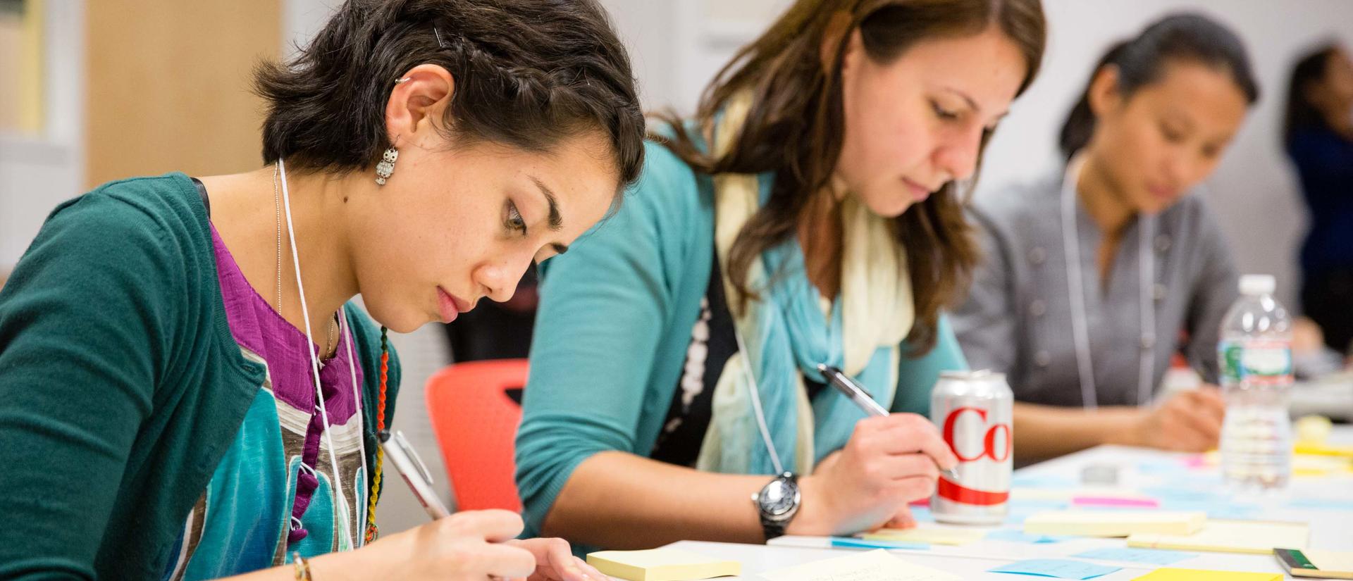 People sitting a a long table writing on multicolored post-it-notes