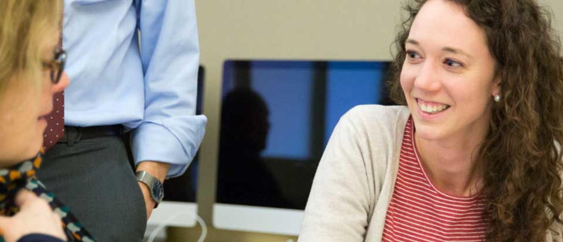 two people sitting and talking with computers behind them